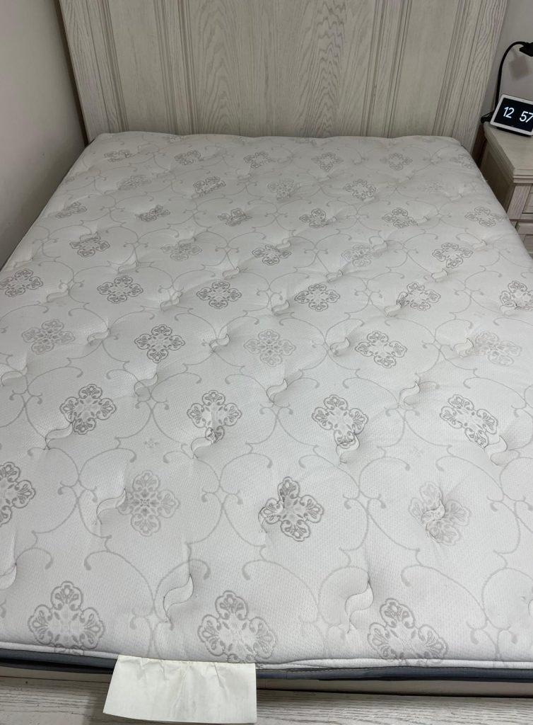 Clean, patterned mattress on a bed frame, freshly restored after a professional deep-cleaning service. The spotless surface showcases NSH Home Services' commitment to thorough mattress cleaning, ensuring a hygienic and comfortable sleep environment